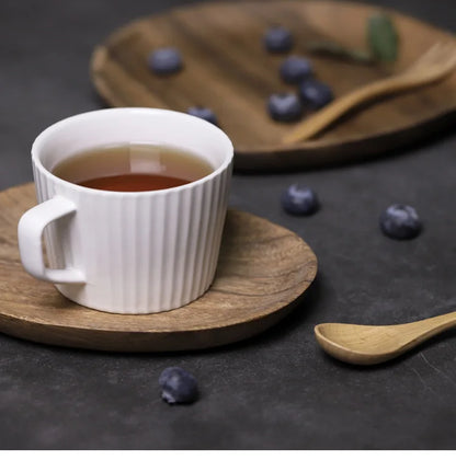 a cup of tea and a spoon on a wooden plate