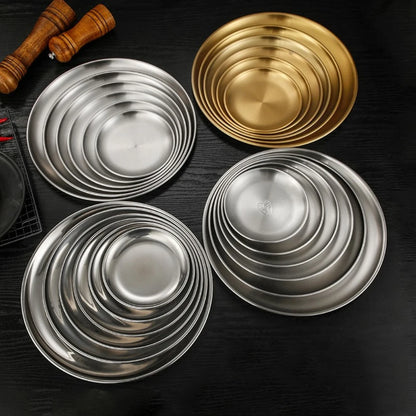 a group of silver and gold stainless steel round plates plates of different sizes