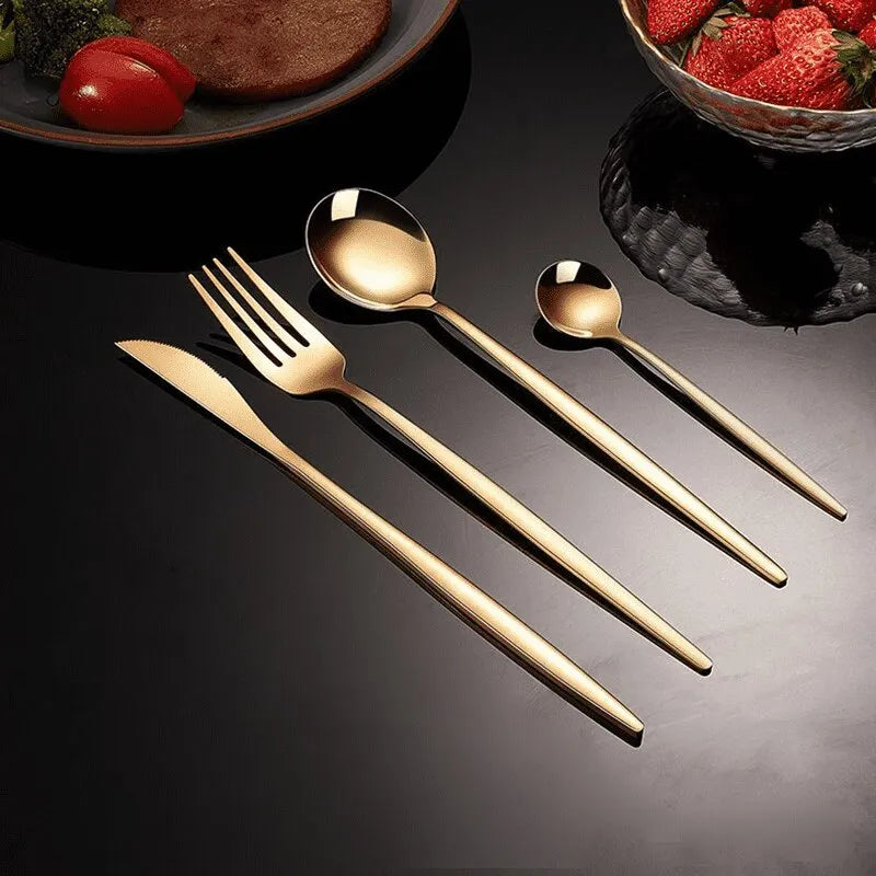 a spoon fork and knife next to a bowl of strawberries